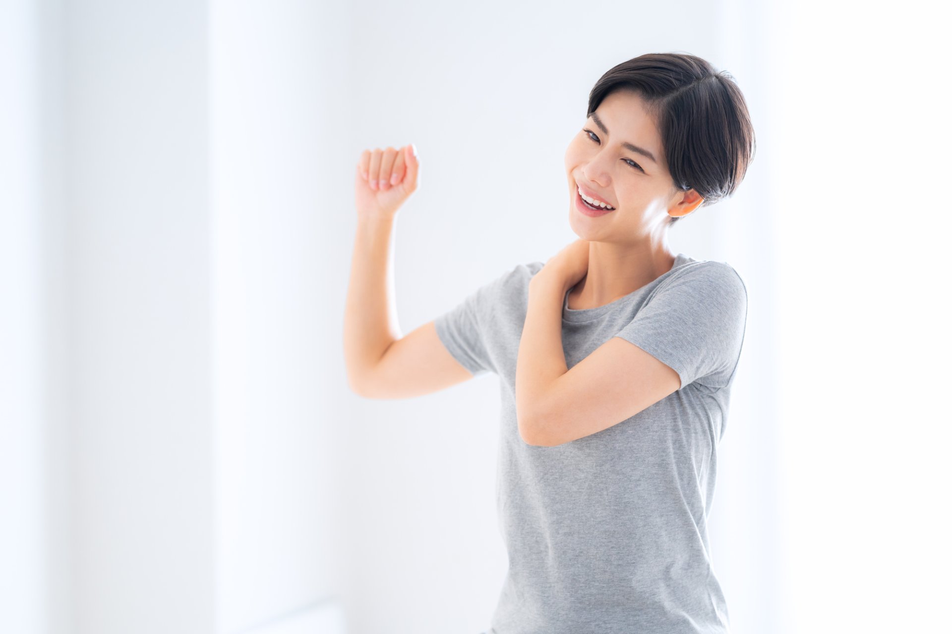 茶色のタオルをかけて施術ベッドに横になる女性の背中に、施術者が両手を添えてもみほぐしをしている様子