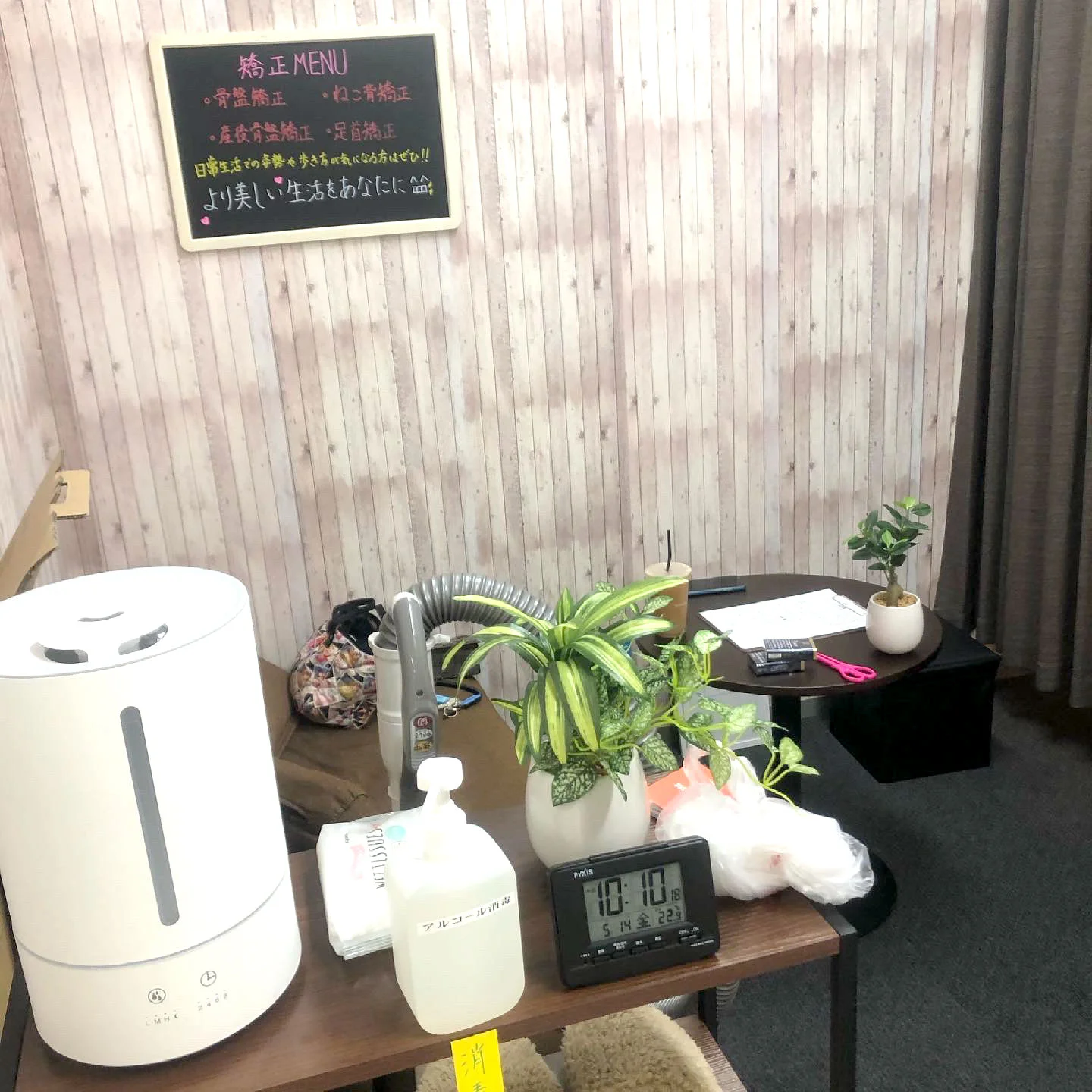 木目調の壁に矯正メニューの黒板と観葉植物、加湿器が置かれたサロンの店内